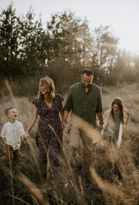 Familie in hohem Gras, glücklich und Händehaltend