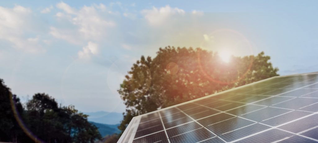 Dach mit Photovoltaikanlage und Sonne im Hintergrund