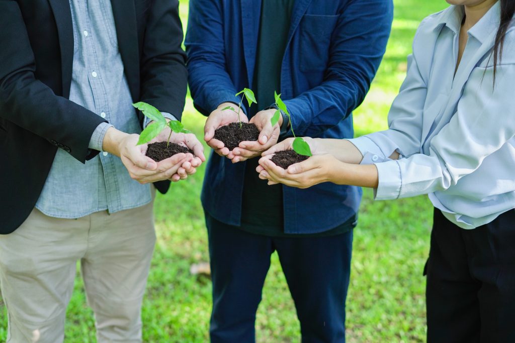 Menschen die in einem Kreis stehen und jeweils eine Pflanze halten
