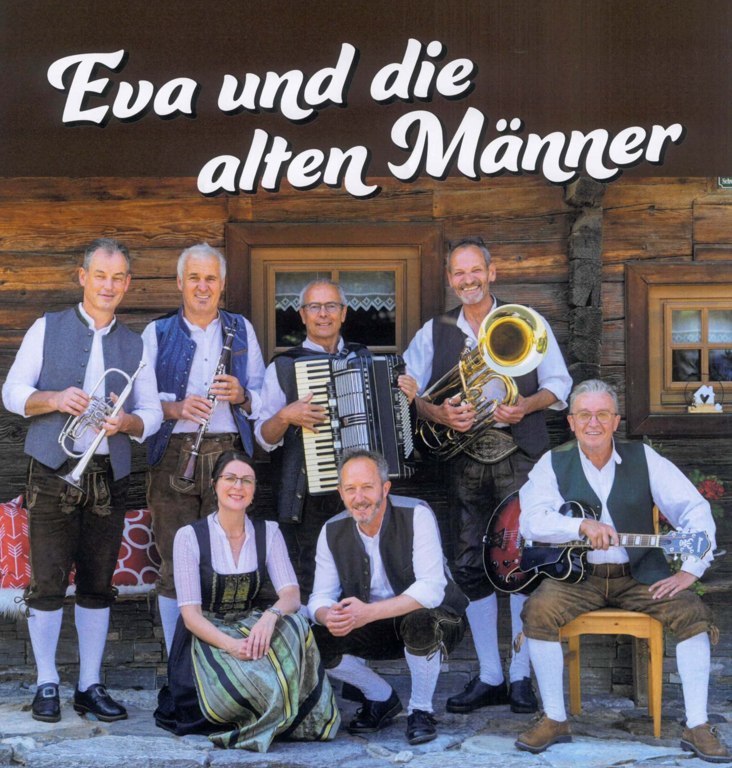 Musikgruppe in traditioneller Kleidung vor Holzhütte mit Instrumenten.