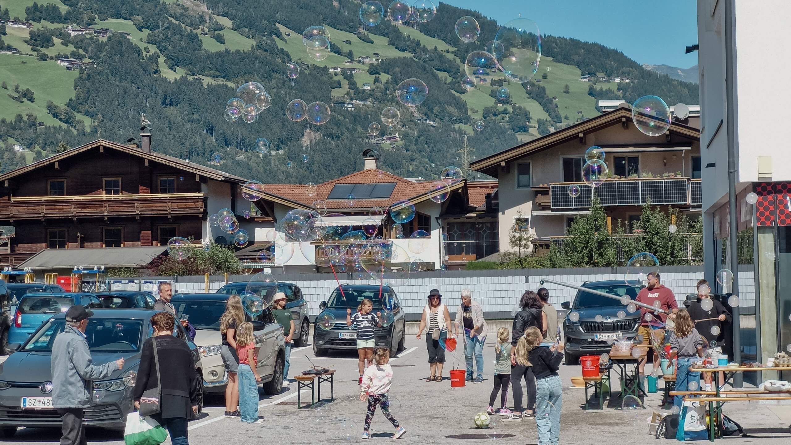 Menschen erzeugen Seifenblasen auf einem Parkplatz mit Bergblick im Hintergrund.