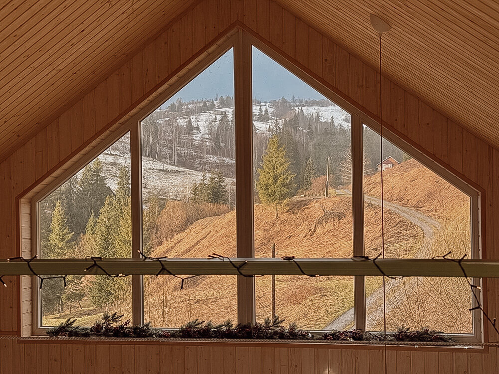 Sanierungsbonus 2026 , Giebelfenster mit Ausblick auf die herbstlichen Berge
